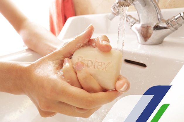 Foco na mão de uma pessoa usando o sabonete Protex para eliminar as bactérias nas mãos