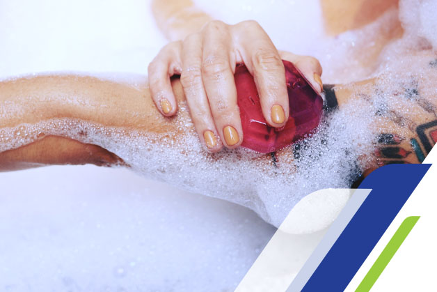 Imagem de uma mulher lavando o braço com a bucha e sabonete em barra de glicerina