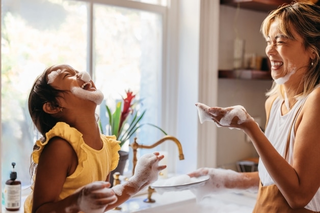 Mãe e filha se divertindo com espuma de sabonete hipoalergênico enquanto lavam as mãos