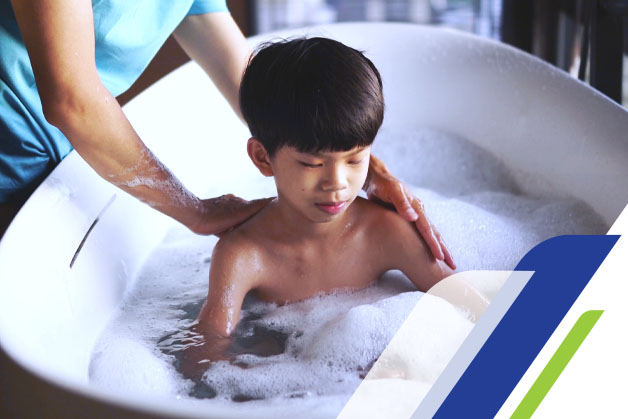 Criança sentada na banheira com a mãe dando banho com sabonete líquido infantil 