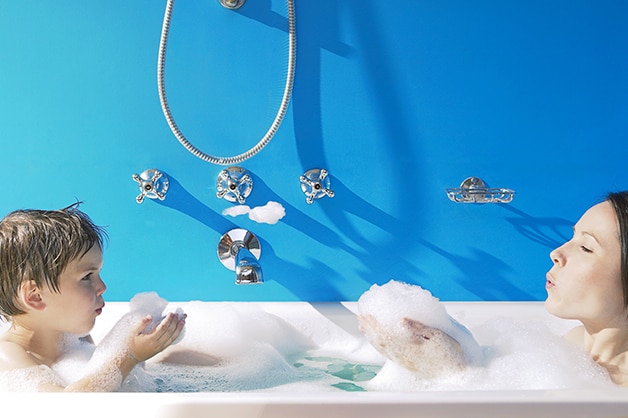 Mãe e filho tomando banho de banheira juntos e brincando com a espuma enquanto aproveitam os benefícios do sabonete Protex.