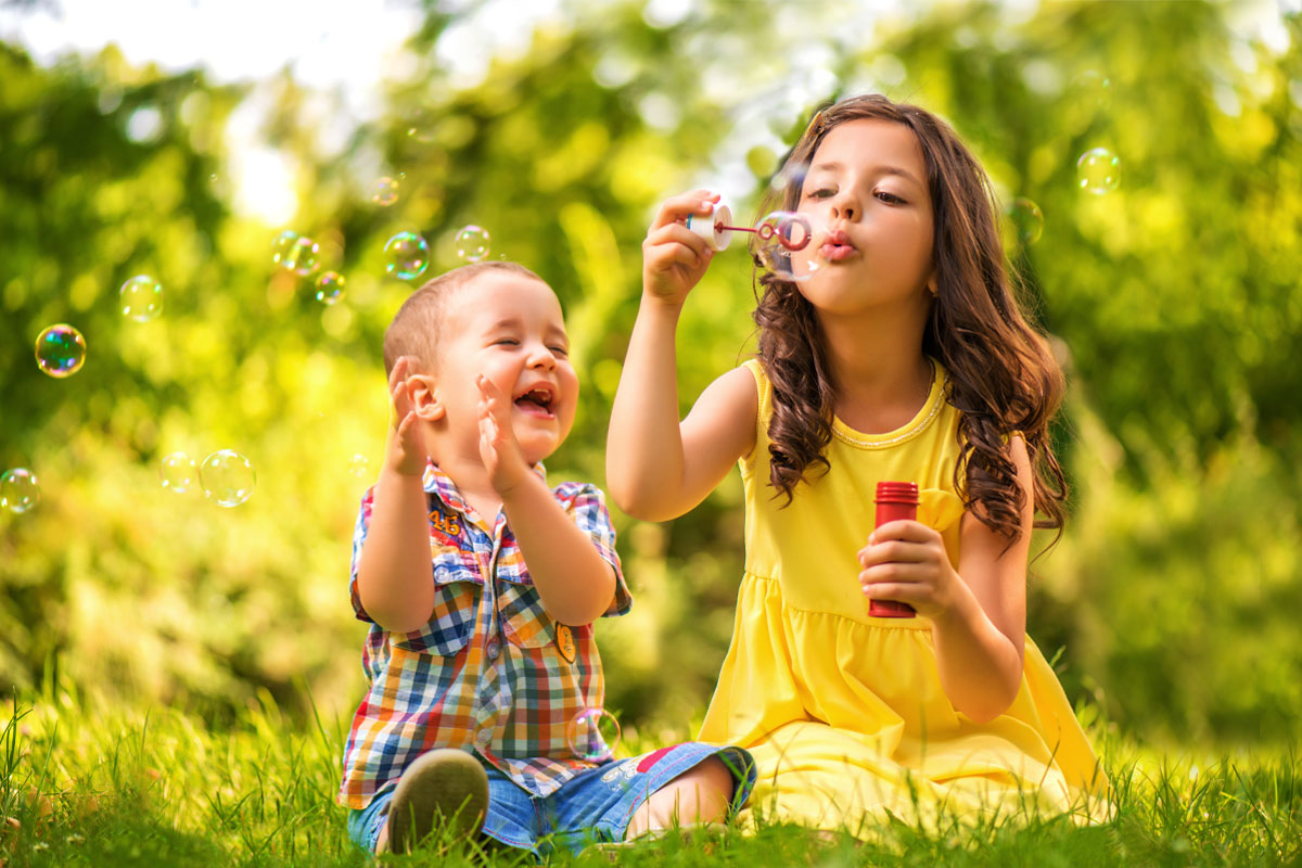 Crianças fazendo caça às bolhas enquanto brincam de banho de mangueira