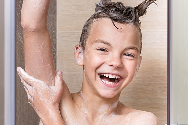 Garoto lavando a axila com sabonete antibacteriano durante o banho