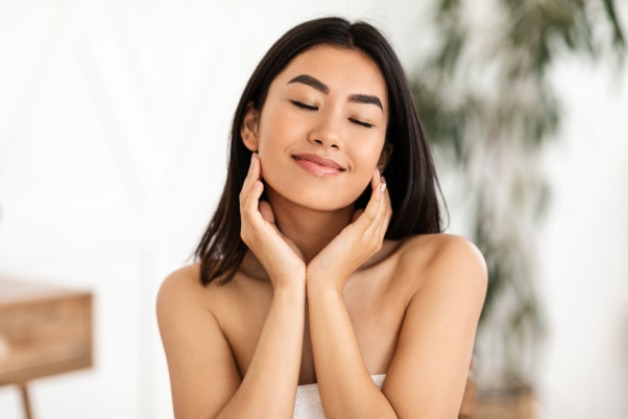 Mulher relaxada e com a pele radiante após aprender a como fazer skincare da forma correta.
