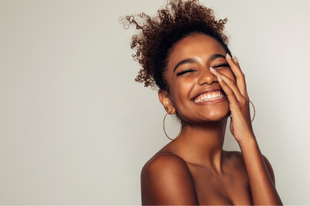 Mulher feliz com a pele saudável e luminosa, resultado do uso diário de sérum