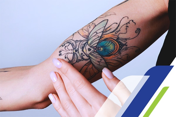 Braço de mulher com uma tatuagem colorida de um escaravelho Braço de mulher com uma tatuagem colorida de um escaravelho
