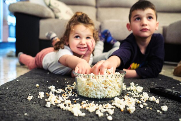 Crianças comendo pipoca e vendo um filme