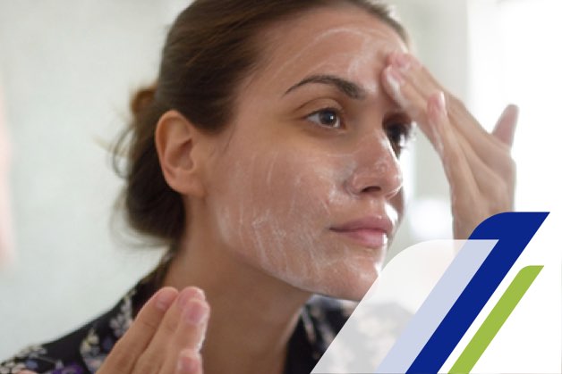 Girl with a cream on her face in front of a mirror