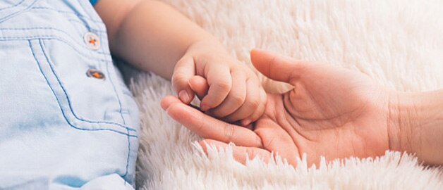 Mão de um bebê agarrando o dedo de sua mãe