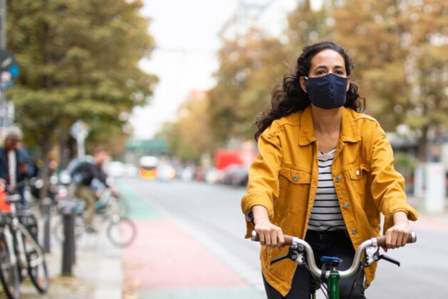 Mulher andando pela cidade de bicicleta, encarando a poluição
