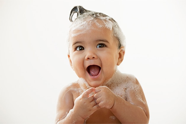 Criança pequena com cabelo ensaboado, se divertindo ao tomar banho com sabonete de glicerina para bebê. Criança pequena com cabelo ensaboado, se divertindo ao tomar banho com sabonete de glicerina para bebê.