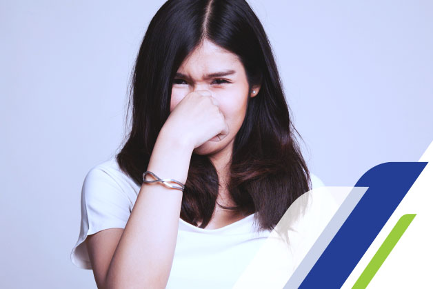 menina com uma camisa branca tampando o nariz porque sentiu um mau cheiro