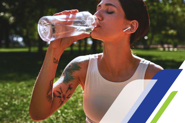 Mulher tatuada depois de uma corrida, bebendo água para evitar infecção na tatuagem