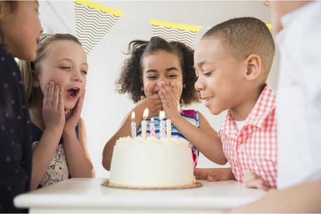 Crianças ao redor do bolo de aniversário em uma festa infantil Crianças ao redor do bolo de aniversário em uma festa infantil